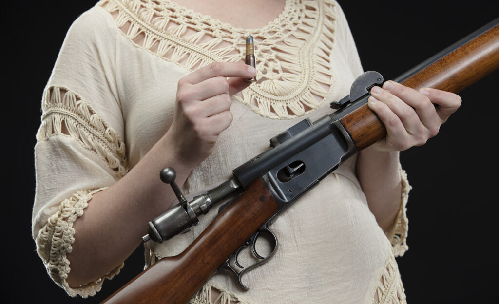 A woman with a .41 Swiss rifle and ammo cartridge